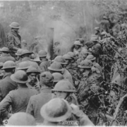 WWI soldiers with their helmets gathered around for a meeting or mail call
